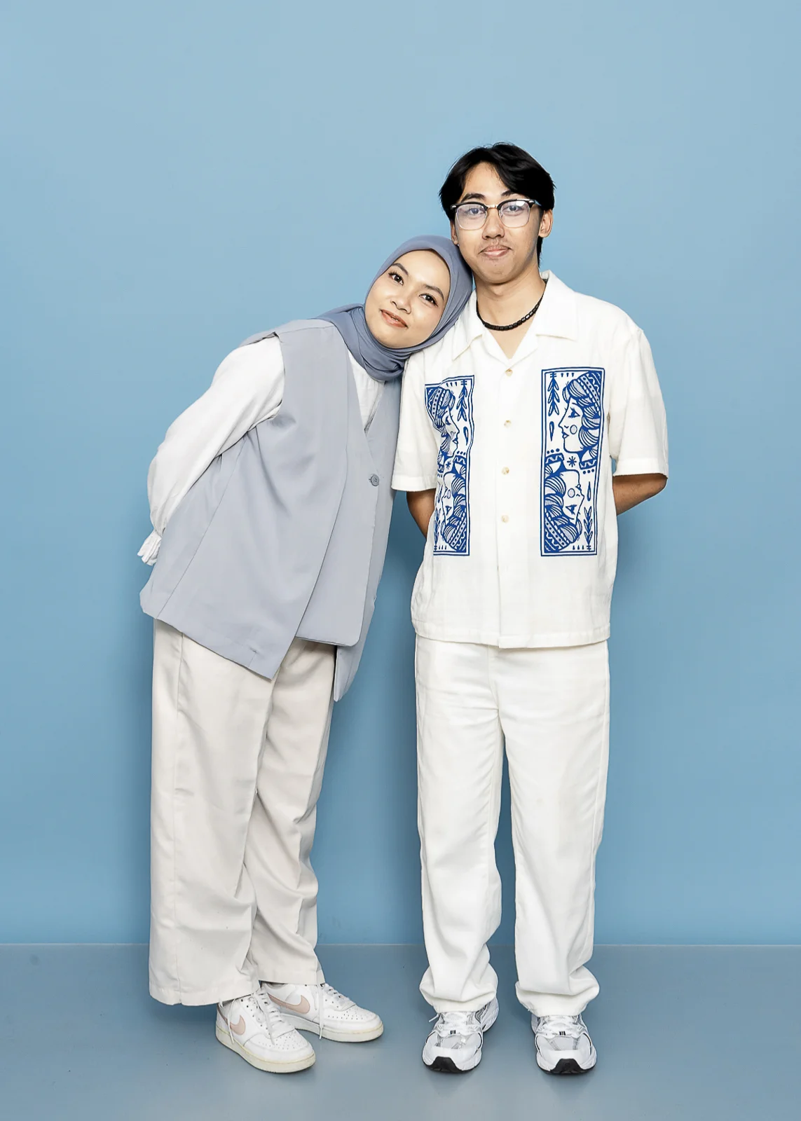 Pasangan berpose di background biru muda dengan dekorasi properti foto.