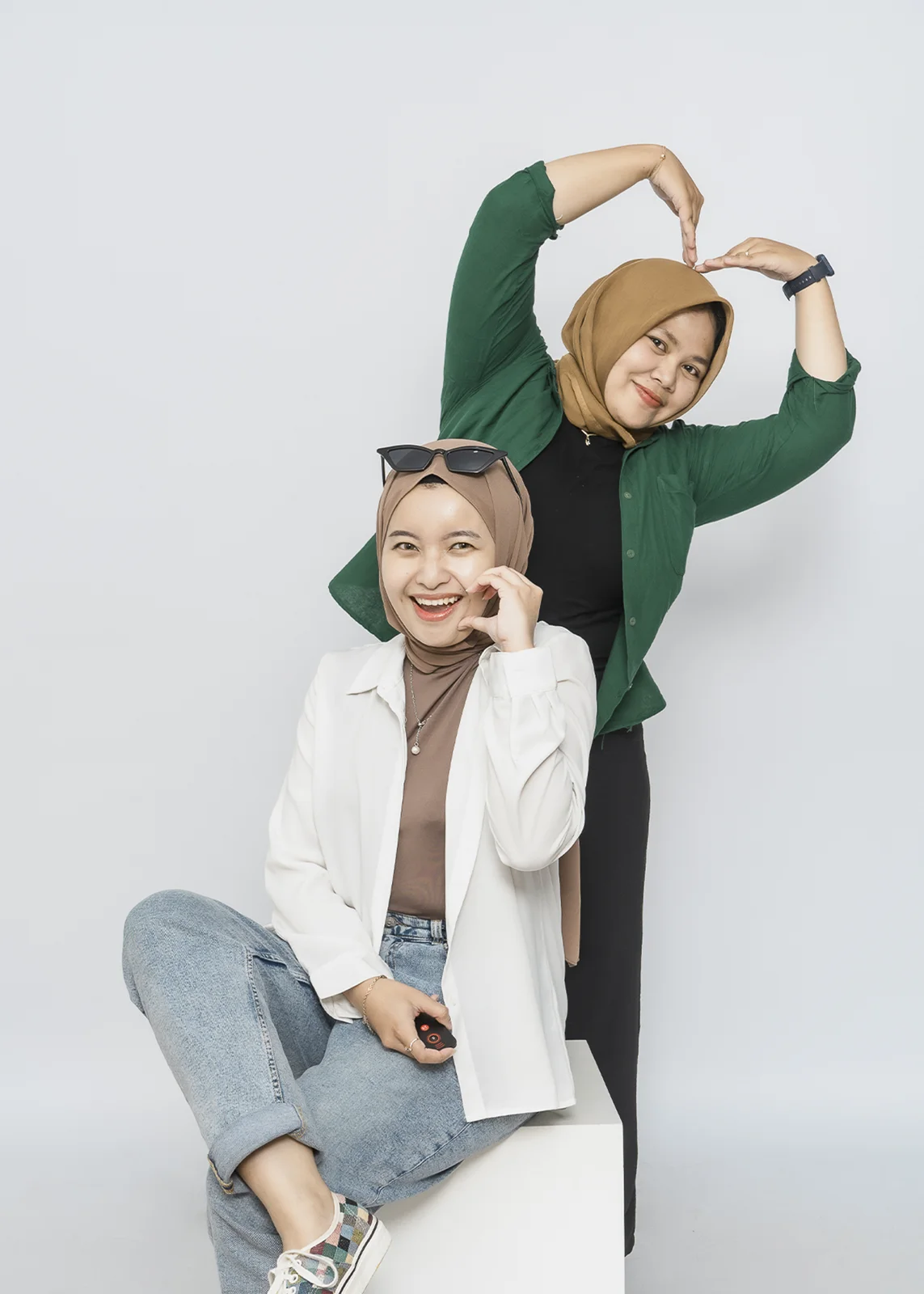 Dua teman berekspresi dengan background putih.